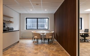 Modern interior view of office space for rent at Essebaan 63, Capelle aan den IJssel, featuring a furnished meeting area with chairs and a small table by a window.