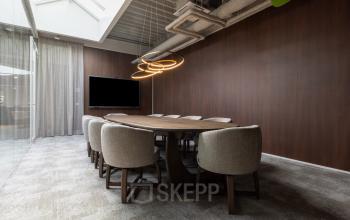 Modern conference room available for office space rental at Essebaan 63, Capelle aan den IJssel, featuring a wooden table, cushioned chairs, and ambient lighting.