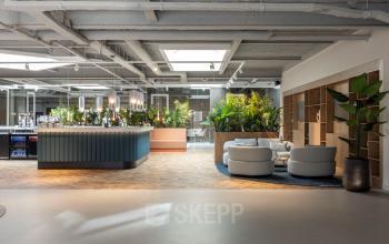 Modern office lounge at Essebaan 63, Capelle aan den IJssel, featuring stylish seating areas and lush greenery, ideal for office space rental and informal meetings.