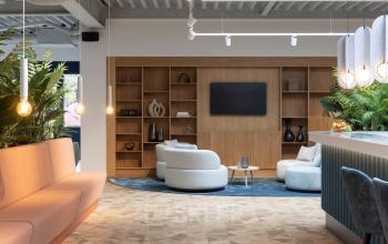 Modern office lounge at Essebaan 63 in Capelle aan den IJssel, featuring stylish seating and a large wall-mounted screen, suitable for office space rental.