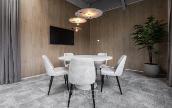 Stylish office interior at Essebaan 63, Capelle aan den IJssel, featuring a round table, chairs, and a wall-mounted TV, ideal for workspace rental.