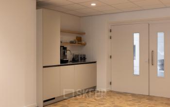 Compact interior view of a pantry area with cabinets, countertop appliances, and a sink in an office space available for rent at Essebaan 63, Capelle aan den IJssel.