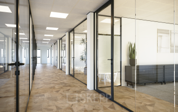 Modern office hallway at Essebaan 63-69 with glass partitioned rooms, potted plants, and parquet flooring, ideal for office space rental.