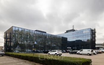 Exterior view of office building located at Essebaan 63, Capelle aan den IJssel, showcasing glass facades and a parking area, ideal for office space rental.