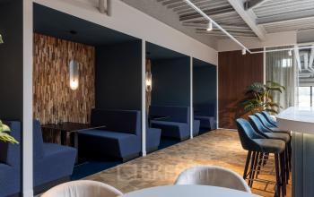 Stylish office lounge with blue booth seating, bar stools, and modern decor at Essebaan 63, Capelle aan den IJssel, ideal for office space rental.