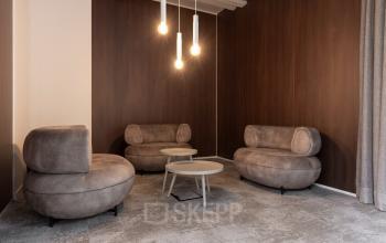 Furnished office lounge area with modern brown sofas and round tables, ideal for office space rental at Essebaan 63, Capelle aan den IJssel.