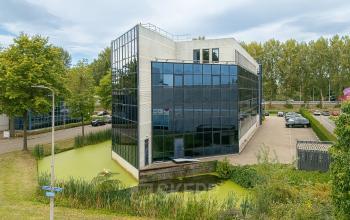 Exterior view of office building at Vlierbaan 20, Capelle aan den IJssel, perfect for office space rental, surrounded by greenery and parking area.