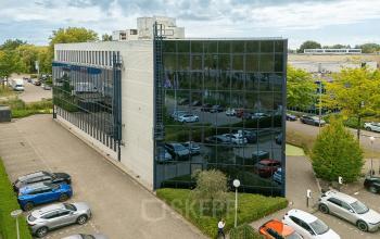 Exterior view of an office building at Vlierbaan 20, Capelle aan den IJssel, showcasing the office space rental location with adjacent parking lot.