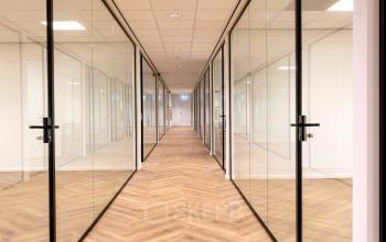 Bright hallway in an office space at Vlierbaan 20, Capelle aan den IJssel, featuring glass doors leading to various offices available for rent.