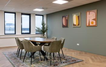 Modern office space at Vlierbaan 20, Capelle aan den IJssel, featuring a round table with chairs on a patterned rug, and abstract art on the wall.