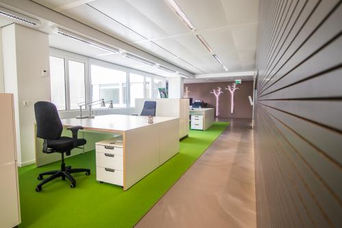 Bright and modern office space at Poortweg 4, Delft, featuring desks, chairs, and vibrant green flooring, ideal for office space rental.