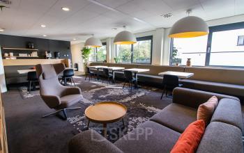 Bright and inviting office space for rent at Marshalllaan 2, Delft, featuring modern furniture with comfortable seating and ample natural light from large windows.
