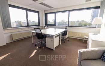 Bright office space at Marshalllaan 2, Delft, featuring large windows with a pleasant view, equipped with desks and chairs for rental office space needs.