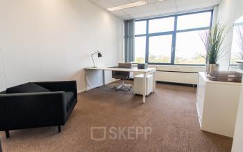 Bright office space to rent at Marshalllaan 2, Delft, featuring a desk and chair with large windows providing natural light. Ideal for office space rental.