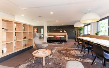 Bright, furnished office space with modern seating and large windows at Marshalllaan 2, Delft. Ideal for office space rental with flexible work areas.