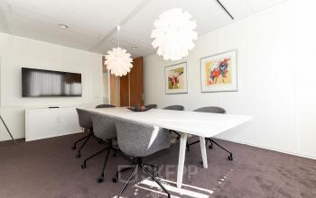 Bright office space at Marshalllaan 2, Delft with modern decor, featuring a long table, chairs, and decorative lighting, ideal for office space rental.