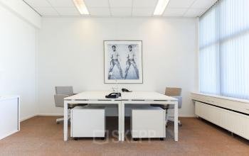 Bright office space for rent at Marshalllaan 2, Delft, featuring two white desks and chairs with a motivational poster on the wall.