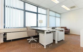 A well-lit, furnished office space for rent at Marshalllaan 2, Delft, featuring modern desks and chairs with large windows providing ample natural light.