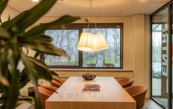 Office to rent at Marshalllaan 2, Delft, featuring a furnished interior with a large wooden table, comfortable chairs, and natural light from surrounding windows. Ideal for office space rental.