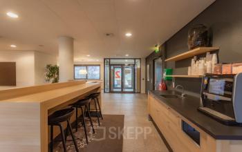 Modern interior view of office space for rent at Marshalllaan 2, Delft, featuring a kitchenette with seating area and ample natural light.