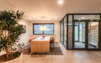 A tastefully furnished office to rent at Marshalllaan 2, Delft, featuring a sleek conference room with a large table, comfortable chairs, and bright lighting. Ideal for office space rental.