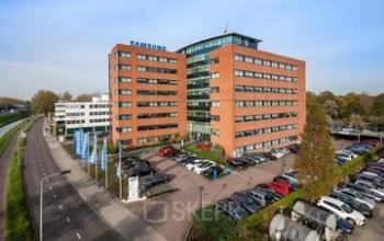 Exterior view of the office building at Olof Palmerstraat 10, Delft, showcasing a modern design, ample parking, and an inviting entrance, ideal for professionals seeking office space rental.