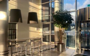 Bright lobby area with tall ceilings and modern lighting at an office to rent in Delft, featuring seating and large windows for natural light.