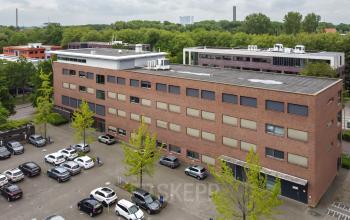Exterior view of an office building at Delftechpark 9, Delft with an adjacent parking area, ideal for office space rental.