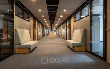 Spacious office hallway at Delftechpark 9, Delft, showcasing modern seating and lighting, ideal for those looking to rent office space. The office to rent offers a sleek, functional design.