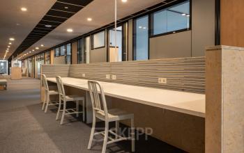 Modern office interior at Delftechpark 9, Delft, featuring a long desk with chairs ideal for office space rental.