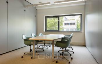 Light-filled office space for rent at Delftechpark 9, Delft, featuring a conference table with chairs and a clear view outside.