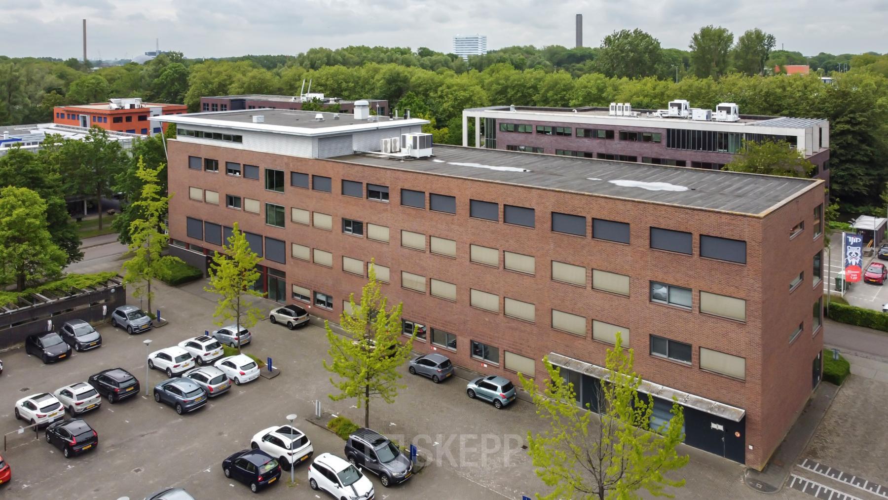 Exterior view of an office building at Delftechpark 9, Delft with an adjacent parking area, ideal for office space rental.