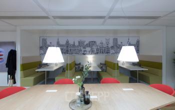 Interior of office space at Willemsplein 2, Den Bosch, featuring a communal work area with modern furnishings and city-themed decor.