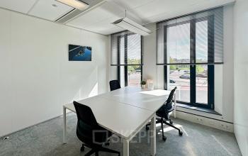 Bright office space for rent at Willemsplein 2, Den Bosch, featuring large windows, modern lighting, and a table with chairs, ideal for meetings.