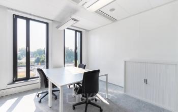 Bright office space at Willemsplein 2, Den Bosch, featuring minimalist furniture and large windows with city views, ideal for office space rental.