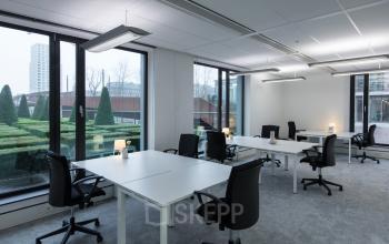 Office space to rent at Willemsplein 2, Den Bosch, featuring large windows, modern furnishings, and a view of a landscaped garden.