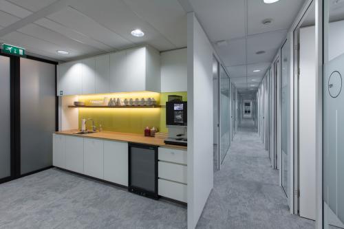 Modern office space rental at Willemsplein 2, Den Bosch featuring a sleek pantry with cabinets and a hallway leading to private offices.