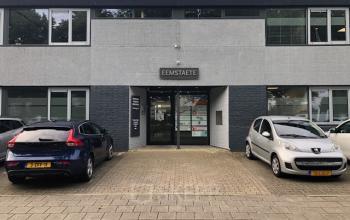 Exterior view of Eemweg 1-9 office building in Den Bosch, featuring parking space with parked cars.