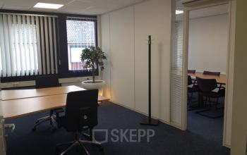 Modern office space rental at Eemweg 1-9, Den Bosch, with neat desks and a meeting room visible through an open door.