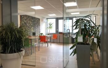 Bright and modern office space at Eemweg 1-9, Den Bosch, with large potted plants and colorful chairs around desks.