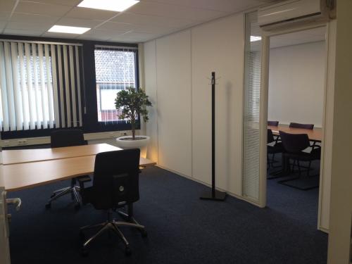 Modern office space rental at Eemweg 1-9, Den Bosch, with neat desks and a meeting room visible through an open door.