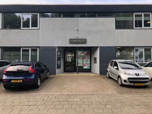 Exterior view of Eemweg 1-9 office building in Den Bosch, featuring parking space with parked cars.