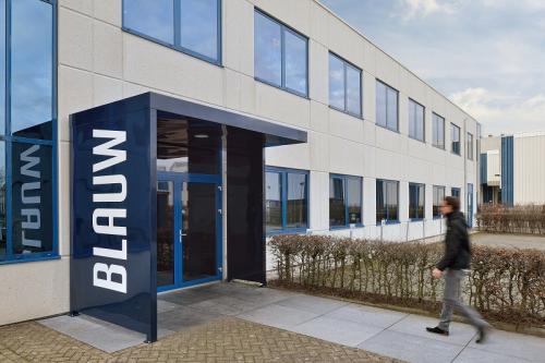 Exterior view of Europalaan 2 office building in Den Bosch, featuring a modern entrance with a pedestrian passing by, ideal for office space rental.