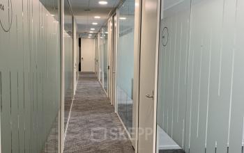 Corridor lined with glass-partitioned offices at Stationsplein 91, reflecting the modern office space rental in Den Bosch.