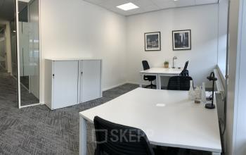 Modern office space rental at Stationsplein 91, Den Bosch, with clean desks, chairs, and enclosed glass spaces for a collaborative environment.