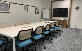 Modern conference room at office space rental located at Stationsplein 91, Den Bosch, outfitted with a large table, chairs, and presentation screen.