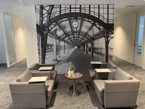 Contemporary office space rental at Stationsplein 91, Den Bosch, featuring comfortable seating and a wall mural depicting a train station.