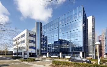 Exterior view of the modern office building at Bruistensingel 400, Den Bosch, highlighting its sleek glass facade and parking area, ideal for office space rental.