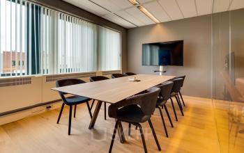 Modern office space rental in Den Bosch with a sleek conference table and wall-mounted TV at Bruistensingel 400. Ideal office to rent for meetings.