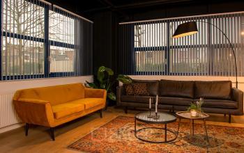 Cozy furnished lounge area in an office to rent at Bruistensingel 400, Den Bosch, featuring vibrant seating and warm lighting. Ideal for informal meetings in office space rental.